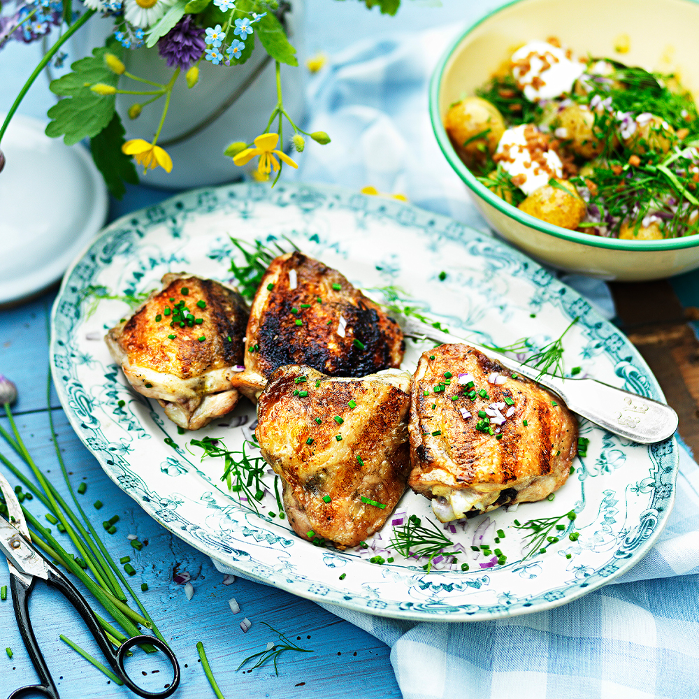 Grillade-kycklinglår-med-sallad-på-färskpotatis,-gräddfil,-rödlök-och-örter
